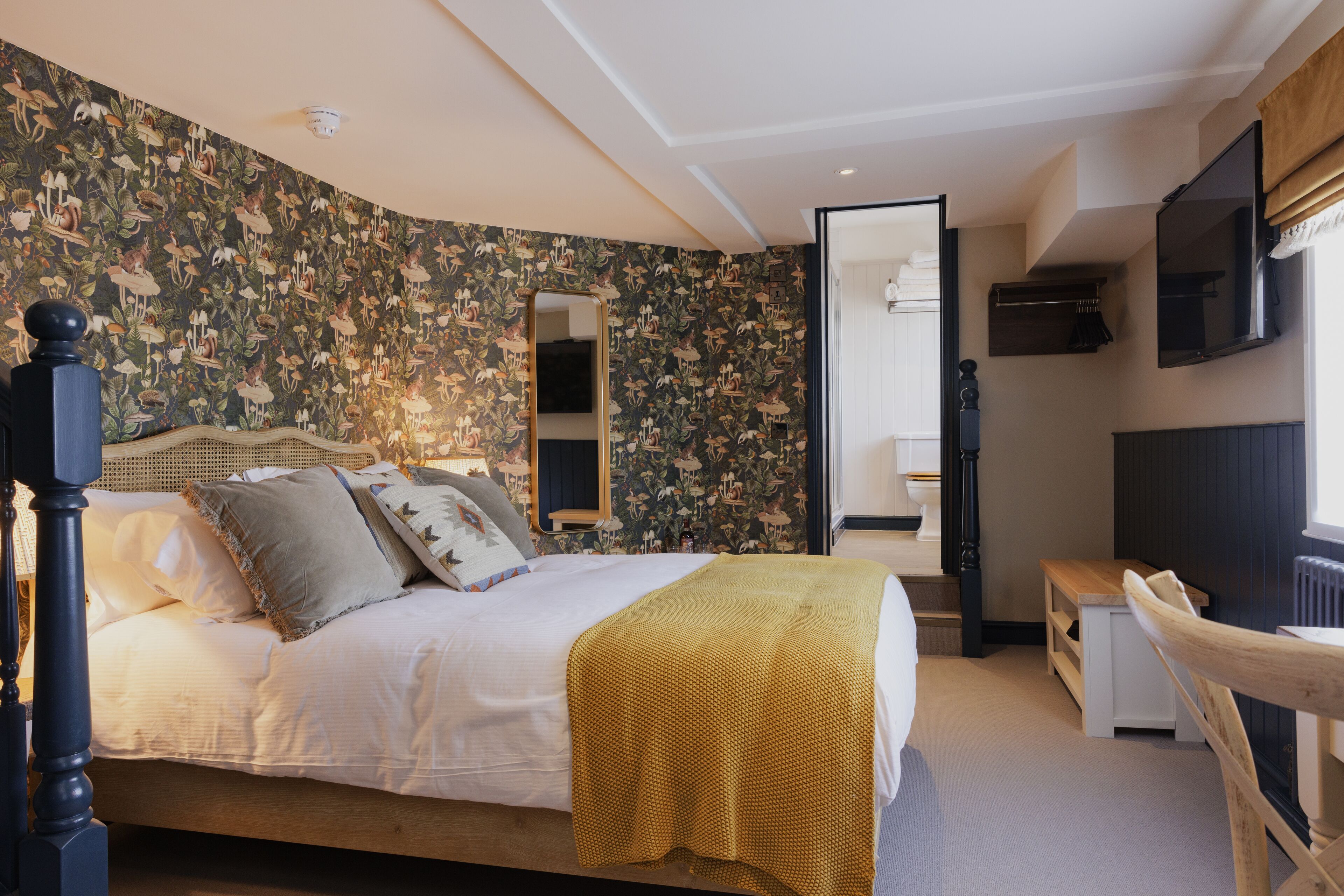 A bedroom with a bed, a mirror, a wooden bench, and a radiator.