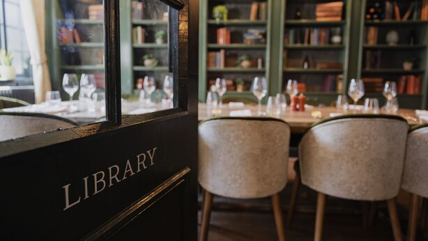 Una biblioteca con estanterías, una mesa lista para comer y sillas.