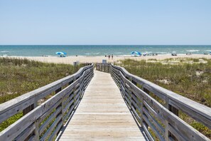 A wooden boardwalk leading to a beach with umbrellas and people. - Southwinds D11-Oceanview Condo (Atlantic Beach)