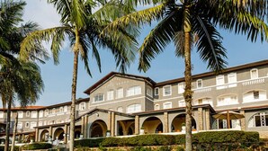 A hotel with a courtyard featuring palm trees and a stone facade.