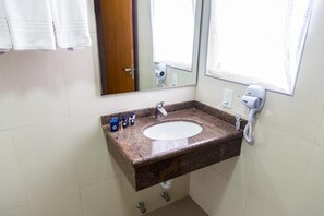 A bathroom with a granite sink, a mirror, a hairdryer, and a towel rack.
