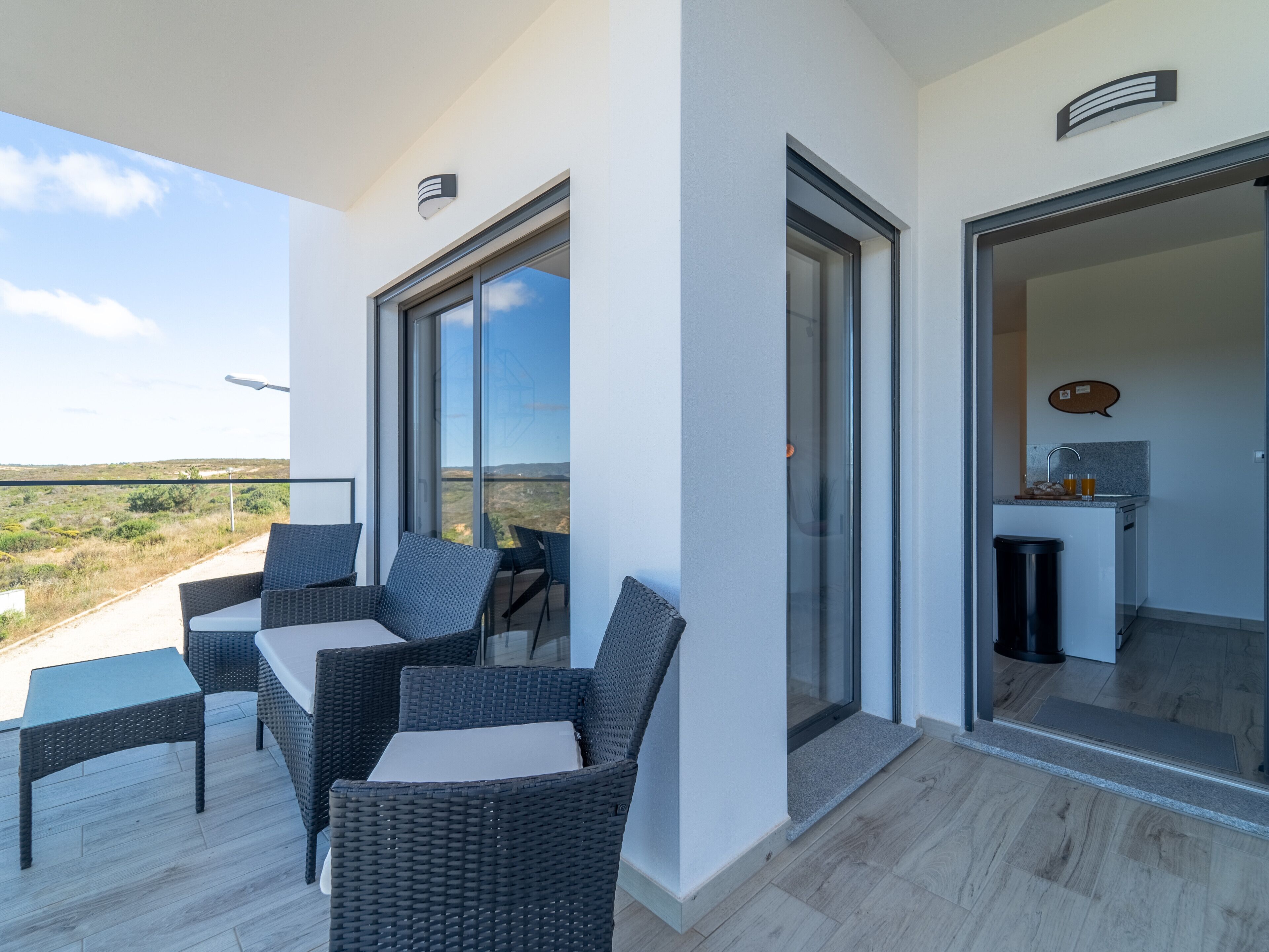 A balcony with wicker furniture and a view of the landscape.