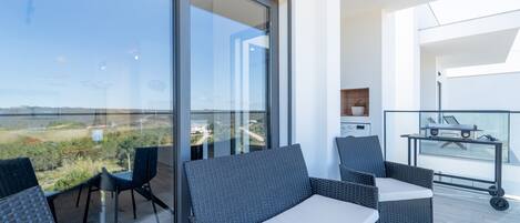 A balcony with wicker furniture, a washing machine, and a cart.