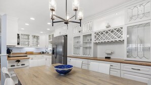 A modern kitchen with white cabinetry, a wooden island, and a stainless steel refrigerator. - Ocean Dreams – Cozy Family Condo Near Beach, Pool & Tennis in Solana Beach (Solana Beach)