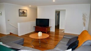 Un salon comprenant un canapé, un téléviseur, une table basse et un tableau accroché au mur.