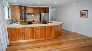 Une cuisine moderne avec des meubles en bois, un îlot central intégré et un réfrigérateur en acier inoxydable.
