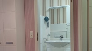 A bedroom with a bed, a wardrobe, and a bathroom visible through an open door.
