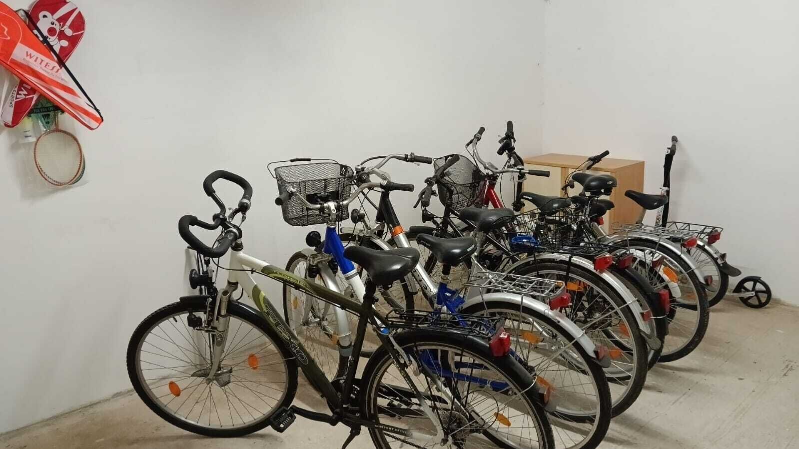Een rij fietsen geparkeerd binnen, met een fietsenrek aan de muur en een kleine tafel op de achtergrond.