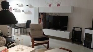 A modern living room with a sofa, a TV, a fireplace, and a dining area.