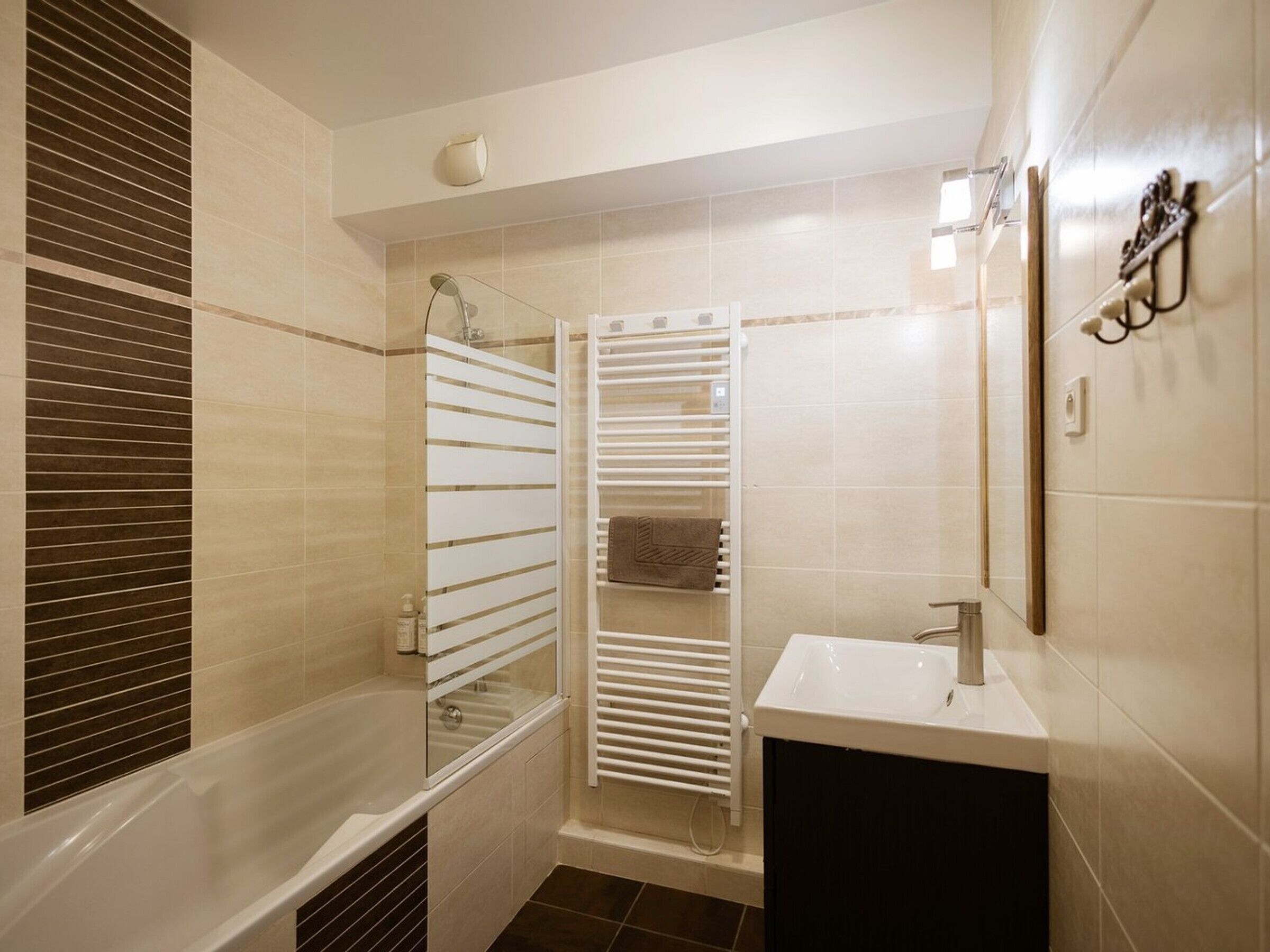 Une salle de bain moderne avec une baignoire, une douche à parois de verre et un lavabo blanc.