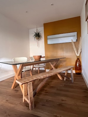 Ein moderner Essbereich mit einem Glastisch, Holzsitzen und einer Pflanze, die von der Decke hängt.
