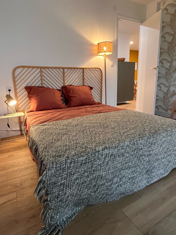 A bedroom with a bed, a nightstand, a lamp, and a wardrobe. - Charmant et Spacieux Appartement T3 en Bord de mer (Canet-en-Roussillon)