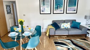 A modern living room with a grey sofa, teal chairs, a glass dining table, and framed artwork on the wall. - Between the beach and the shops (Portsmouth)