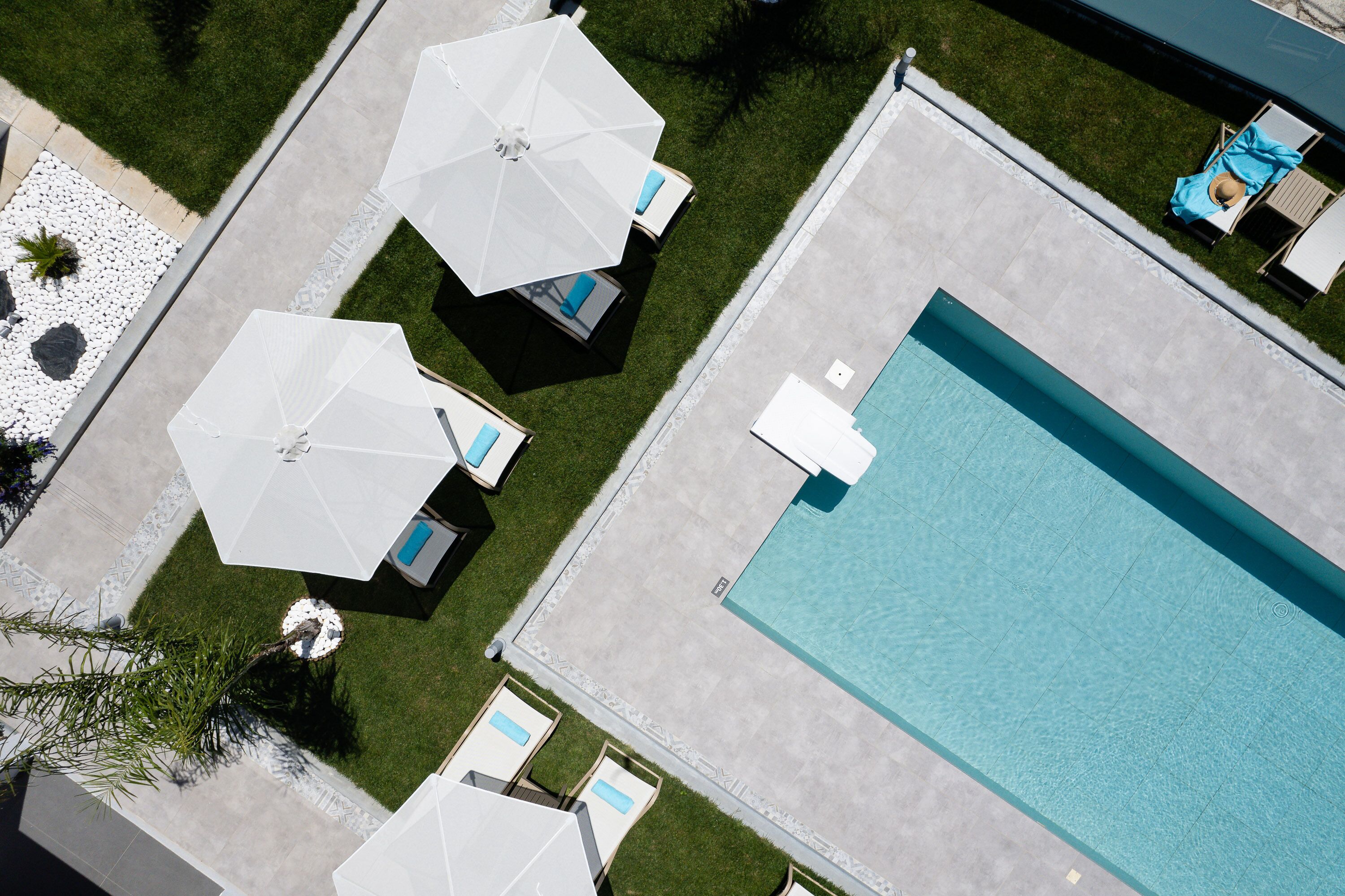 An aerial view of a swimming pool area with multiple lounge chairs and umbrellas.