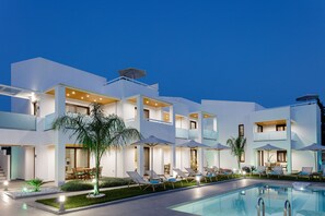 Ein modernes Hotel mit Pool, Sitzgelegenheiten im Freien und Sonnenschirmen.