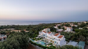 A coastal residential area with modern white buildings, a swimming pool, and a view of the sea. - Coconut Palm Paradise (Rethymno)