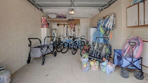 A garage with bicycles, a wheelchair, and storage bins. - A Quaint and Serene Neighborhood in North Naples (Naples)