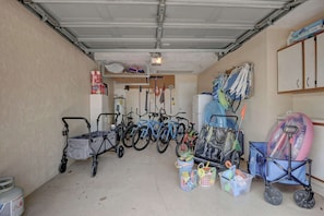 A garage with bicycles, a wheelchair, and storage bins. - A Quaint and Serene Neighborhood in North Naples (Naples)