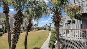 A residential area with palm trees, a pathway, and a building with a covered patio. - Beach View, Pet Friendly, 3 BR End-Unit Steps from Beach ~ Sand and Surf (Cape San Blas)