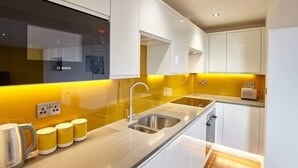 A modern kitchen with white cabinets, a stainless steel sink, and a Bosch appliance. - Host & Stay | The Royal Hideaway (Whitby)