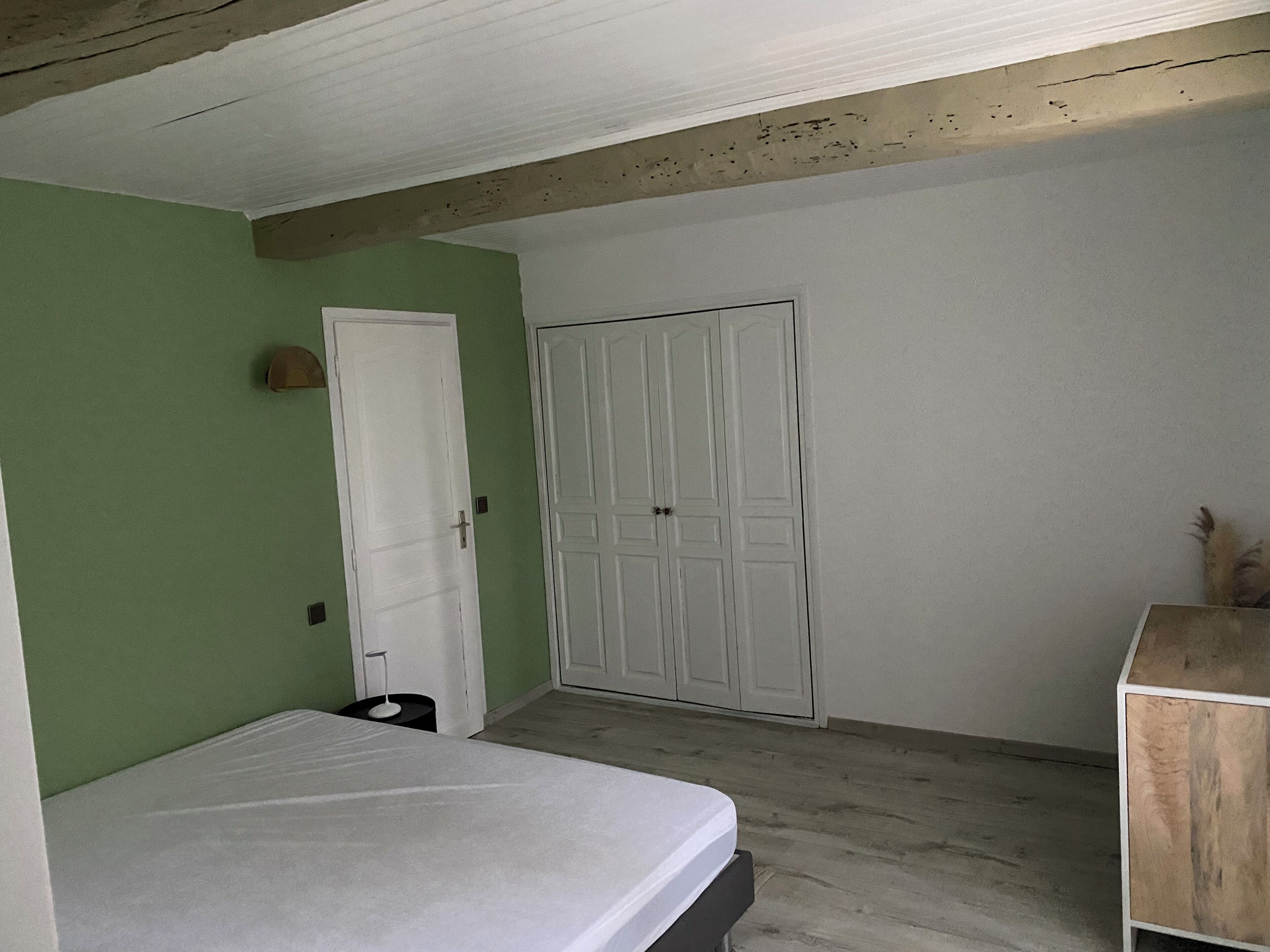 A room with a bed, a wardrobe, and a small table.