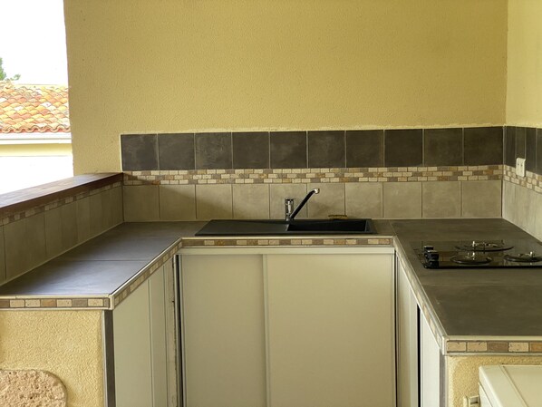 Una cocina compacta con un lavamanos, estufa y encimera.