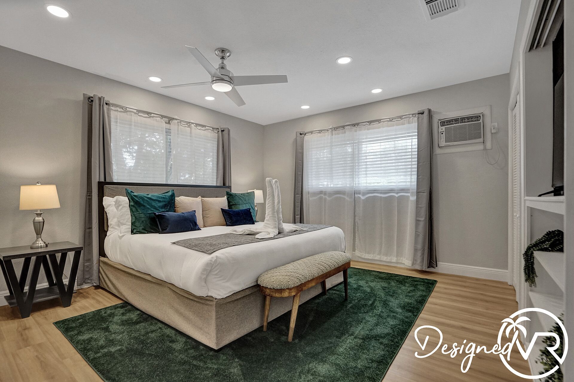 A bedroom with a bed, bedside table, lamp, and a ceiling fan.