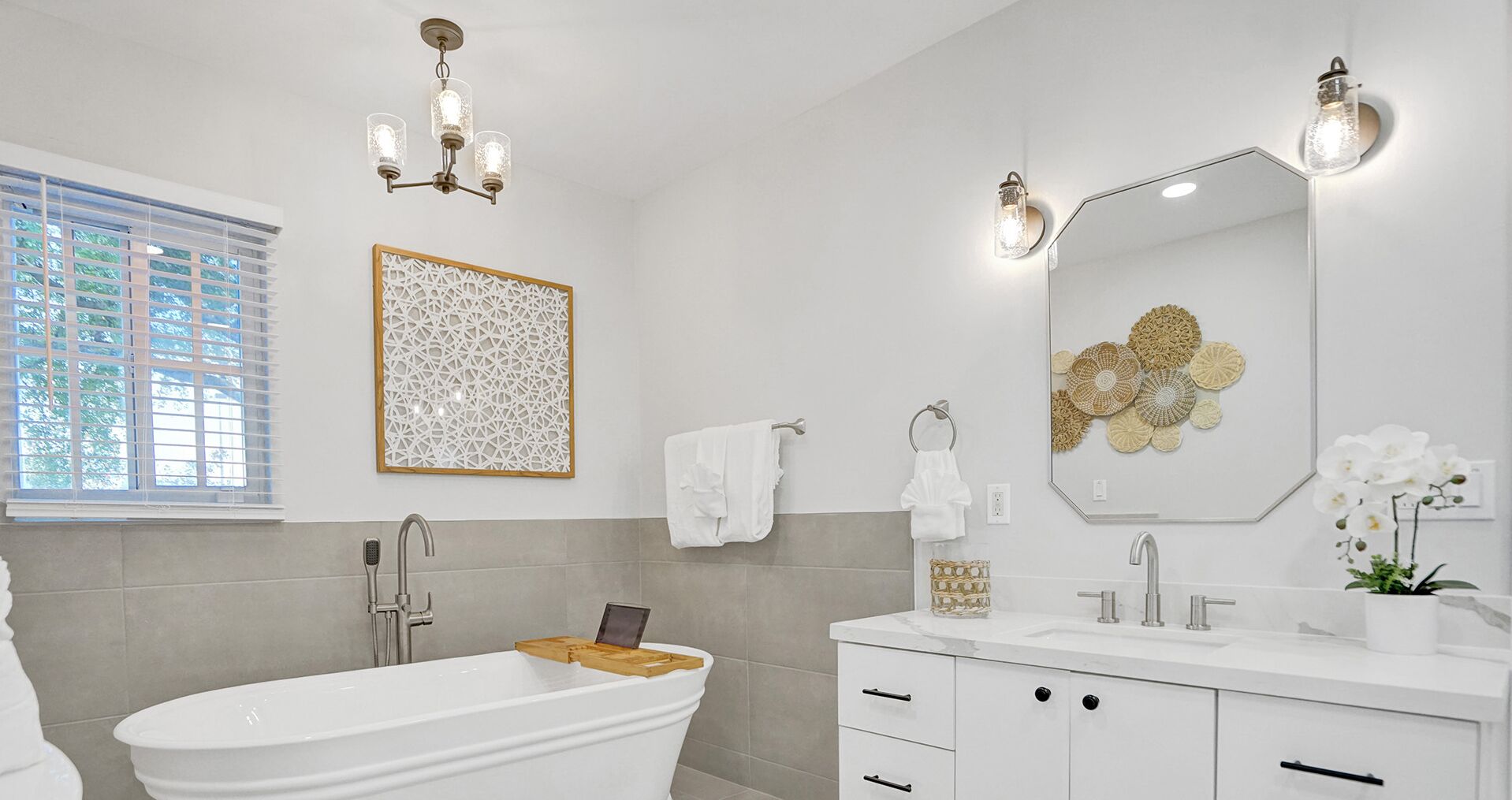 Un bagno moderno con una vasca freestanding, uno specchio grande e un elemento decorativo a parete.
