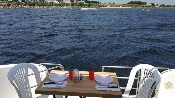 Ett bord uppdukat på en båt med utsikt över havet och den avlägsna kustlinjen.