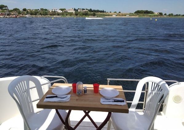 Una mesa colocada en un barco, con vista al mar y la costa distante.