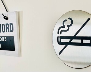 A wall-mounted sign with a no-smoking symbol and a hanging sign with the word "WORD" and the number "085". - Impeccable 2 Bedroom House in Bicester (Bicester)