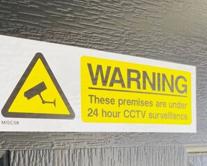 A warning sign indicating 24-hour CCTV surveillance. - Impeccable 2 Bedroom House in Bicester (Bicester)