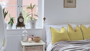 A bedroom with a bed, bedside table, and window with plants. - Impeccable 2 Bedroom House in Bicester (Bicester)