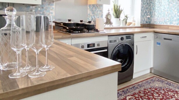 A modern kitchen with a wooden countertop, built-in appliances, and a washing machine. - Impeccable 2 Bedroom House in Bicester (Bicester)