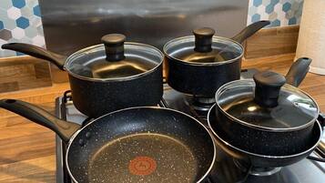Four black pots with lids on a stove.