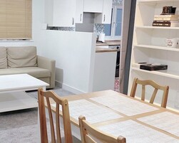 A compact living space with a kitchenette, a dining area with a table and chairs, and a sofa.