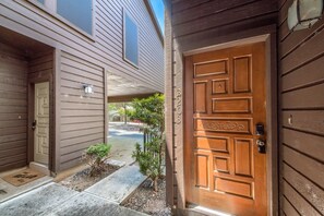 A residential entryway with a wooden door, a mailbox, and a small garden area.