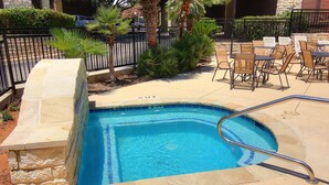 A swimming pool with a 3 ft depth sign, surrounded by a stone wall and a metal fence.
