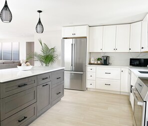 A modern kitchen with white cabinets, a stainless steel refrigerator, a microwave, and a coffee maker on the countertop.