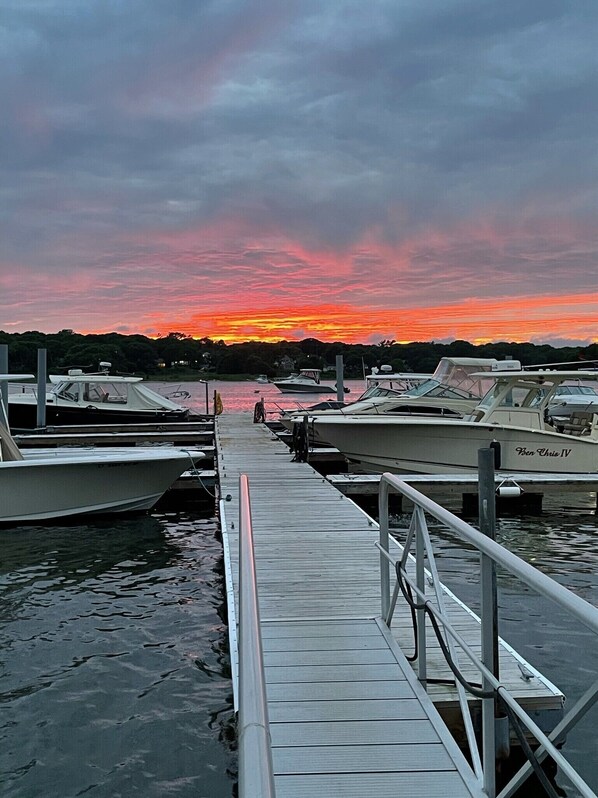 A marina with docked boats and a wooden pier leading to the water.