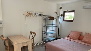 Ein Schlafzimmer mit Bett, Schreibtisch, Stuhl, Kleiderschrank und Fenster.