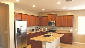 Una cocina moderna con armarios de madera, electrodomésticos de acero inoxidable y una isla con encimera de granito.