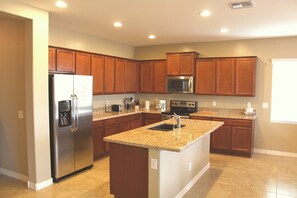 Una cocina moderna con armarios de madera, electrodomésticos de acero inoxidable y una isla con encimera de granito.