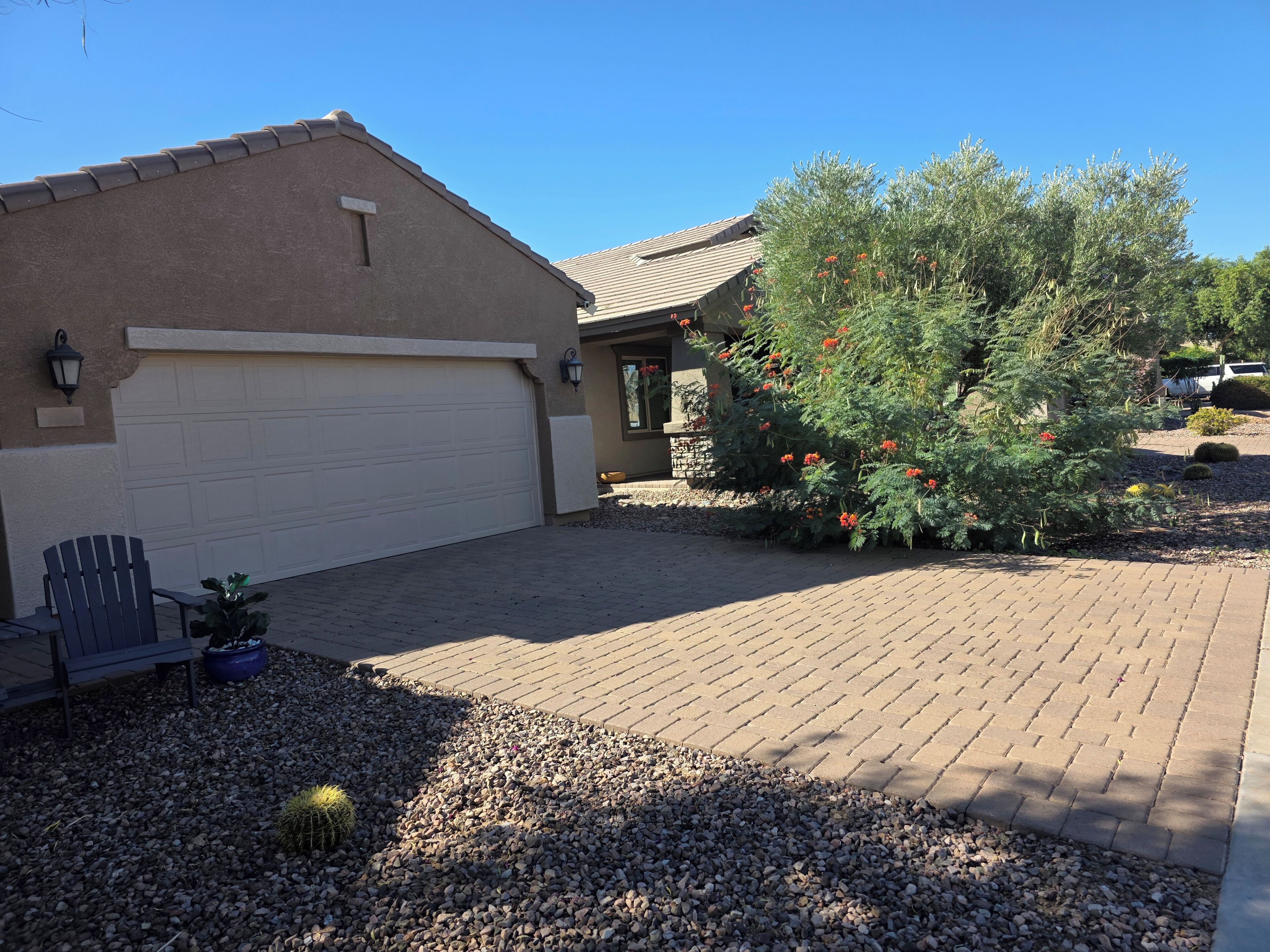 A residential driveway with a garage, a patio area with a bench, and a cactus plant.