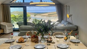 A dining area with a table set for a meal, overlooking a scenic coastal view. - Porth Beach (Newquay)