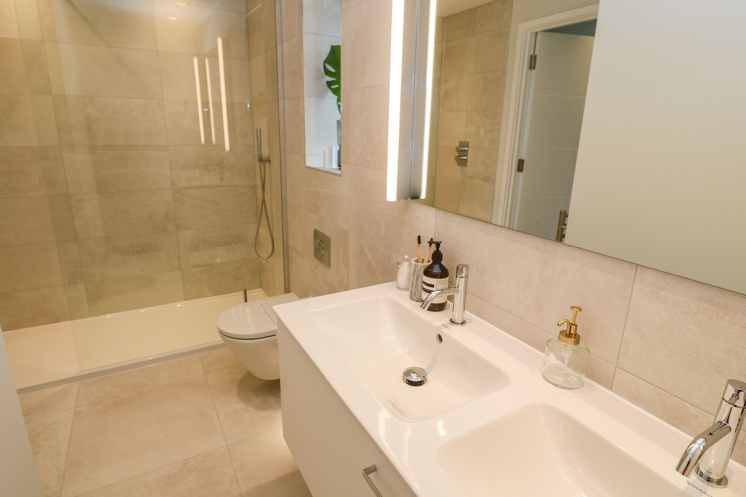 A modern bathroom with a shower, toilet, and a large sink with a mirror.