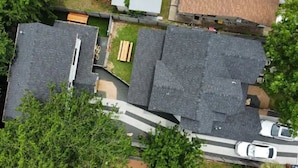 Oversigtsbillede af et boligområde med flere huse, en indkørsel og en parkeret bil.