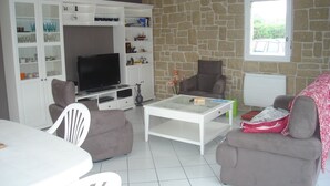 A living room with a TV, two sofas, a coffee table, and a stone wall.