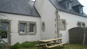 A house with stone window frames, a wooden door, and a picnic table in the yard.