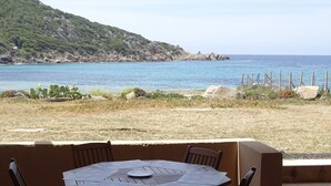 Mesa com cadeiras em frente a vista do mar e uma encosta.